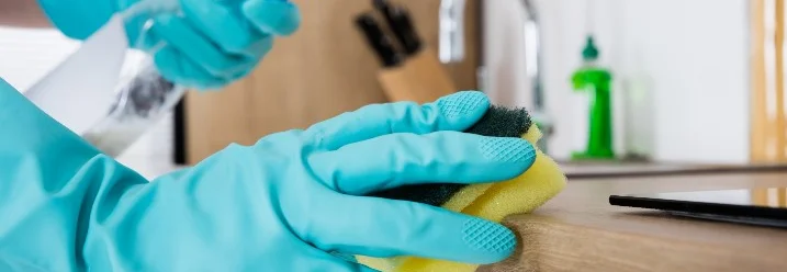 Person reinigt Arbeitsplatte mit Schwamm